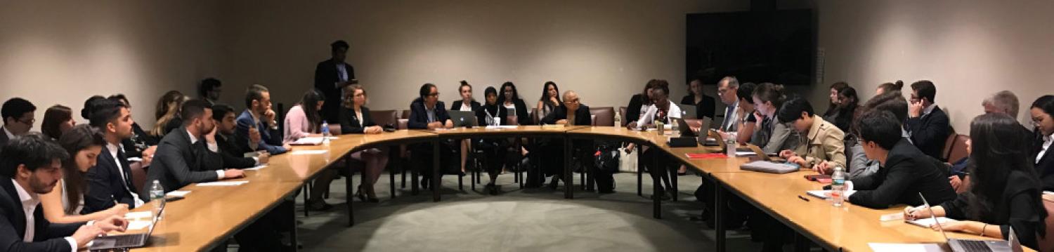 People sitting around a table at the UN, discussing.