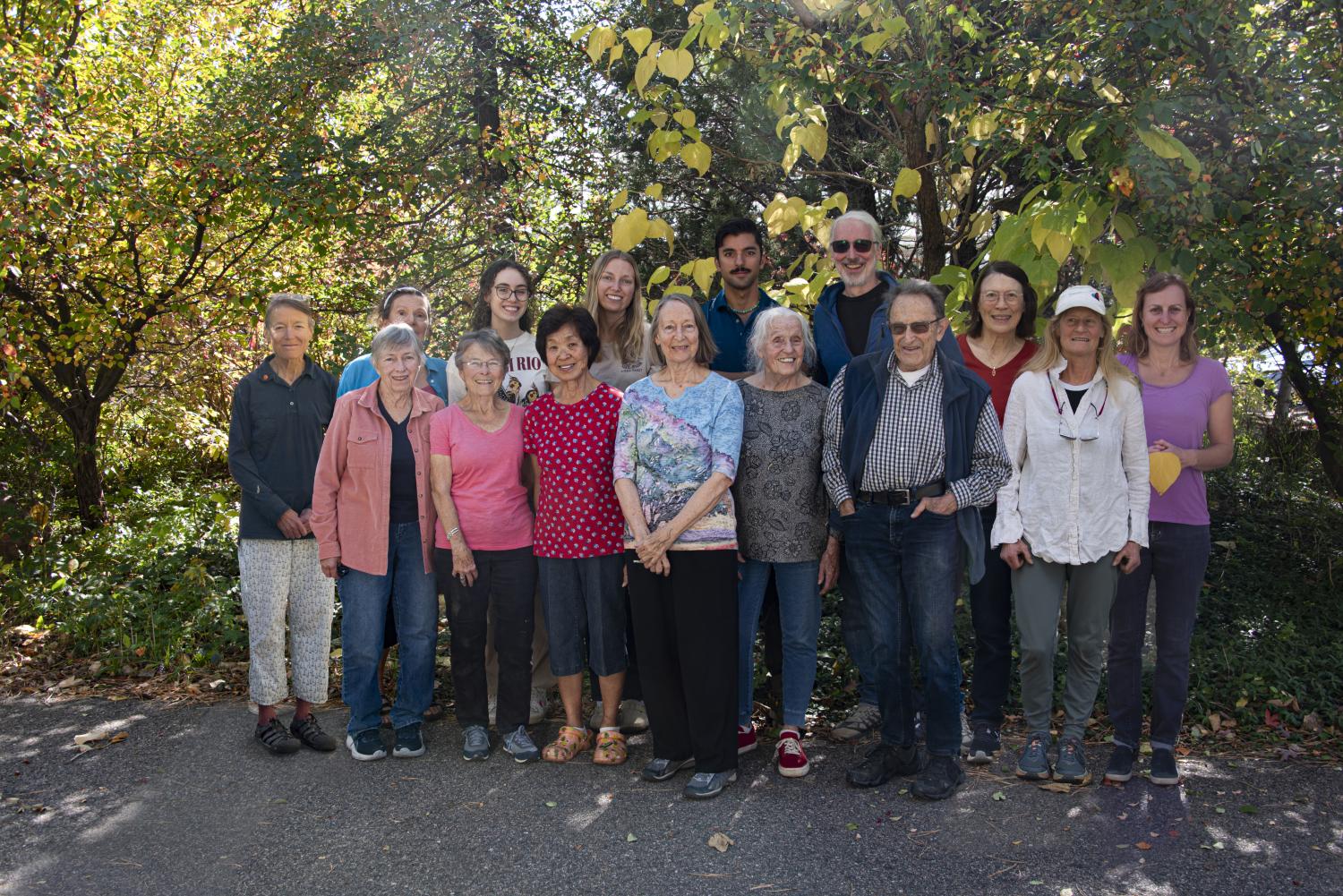 Group photo of greenhouse volunteers in front of fall trees