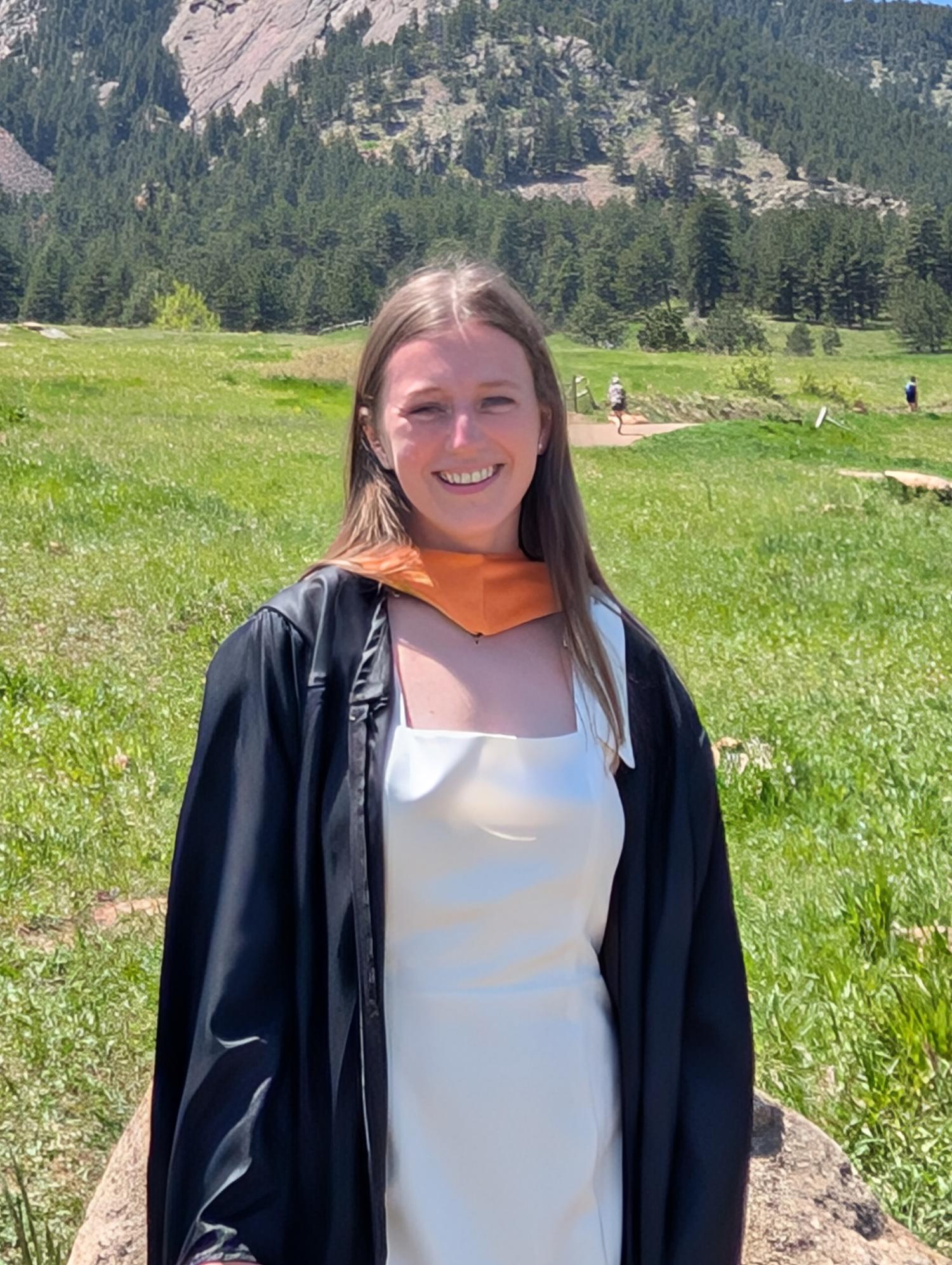 MiKyla in front of Flatirons in graduation gown.