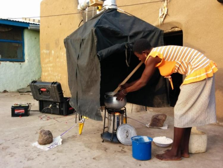 a cook prepares TZ, a staple dish in northern Ghana, with the Phillips improved biomass cookstove while the research team monitors emissions from the process