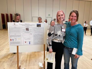 Undergraduate Emma Shaffer and graduate student Chelsea Taylor at the 2023 CU Undergraduate Research Day in front of Emma's poster presentation