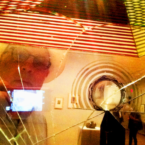 A glitched image of a gallery show with the artists face transposed on top