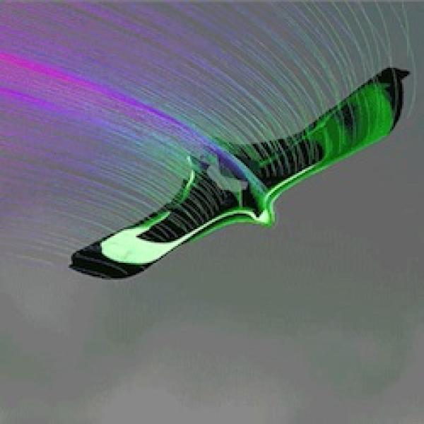 A digitally edited image of a green and black, birdlike drone flying through the gray sky.