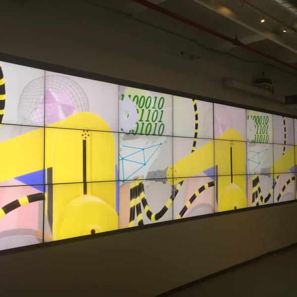 A digital art display showing yellow machines, binary code and wire frame figures.