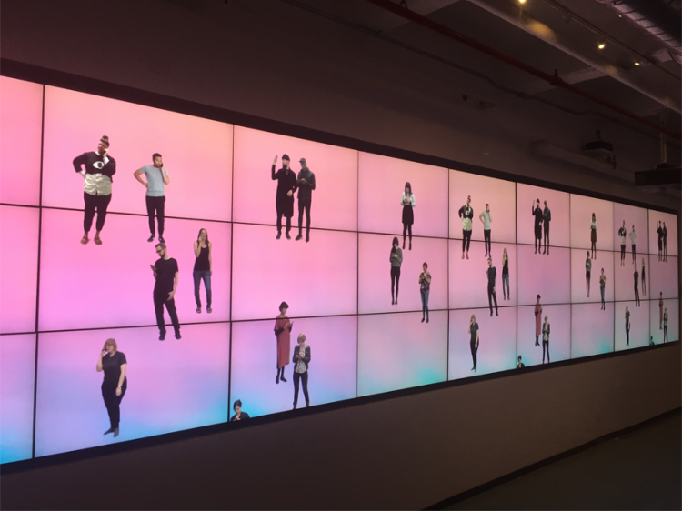 A digital art display depicting cut outs of people on a pink, yellow and blue gradient background.