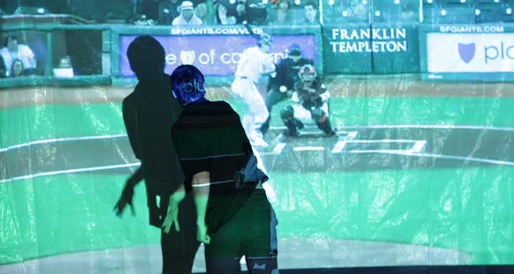 A student interacts with a digital projection of a baseball field.