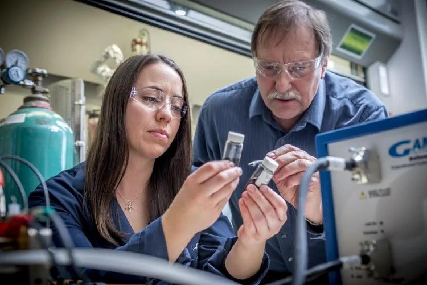Al and a graduate student looking at two vials containing powder.