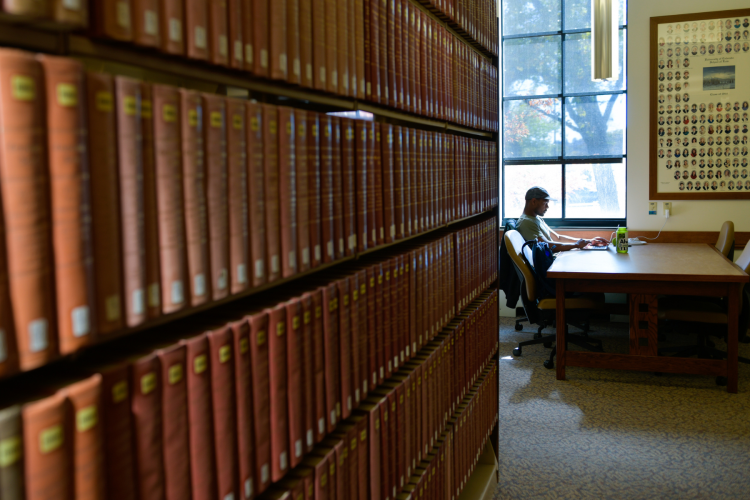 photo of bookshelf and student sitting at desk