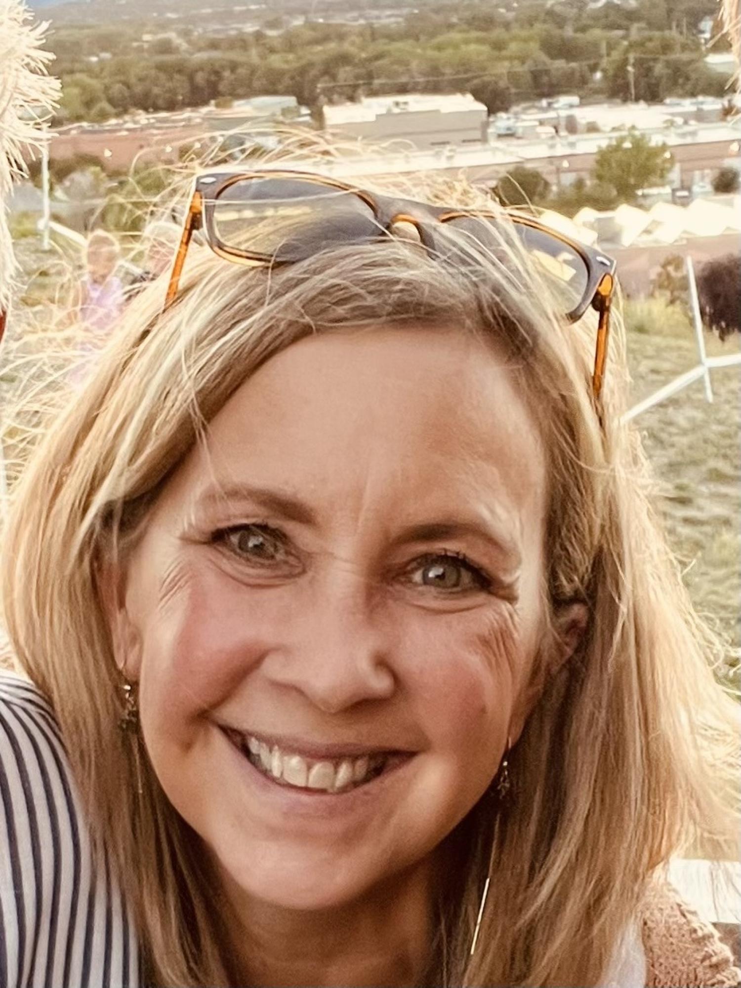Image of smiling woman with blonde hair and sunglasses on her head.