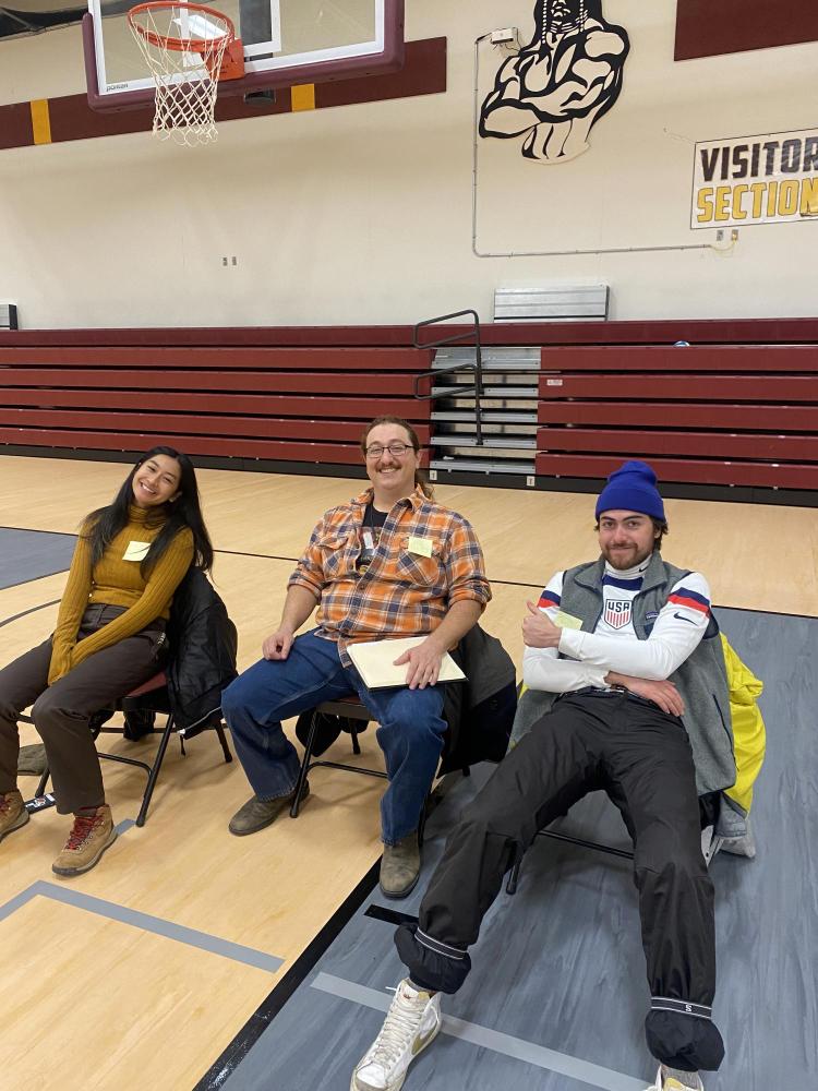 Three people sitting at a basketball court