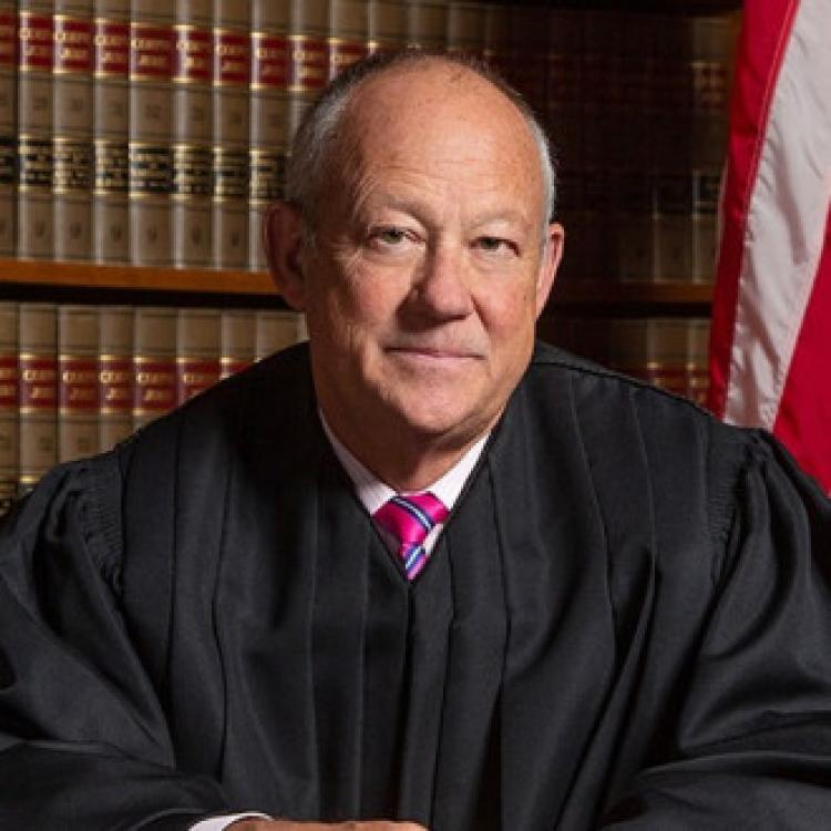Portrait of Judge Tymkovich in front of law books and American flag