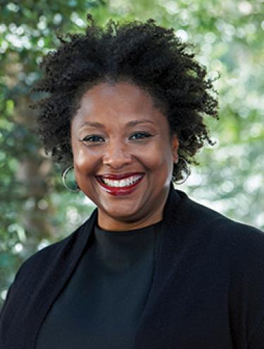 Portrait of Professor Deborah Archer in front of greenery