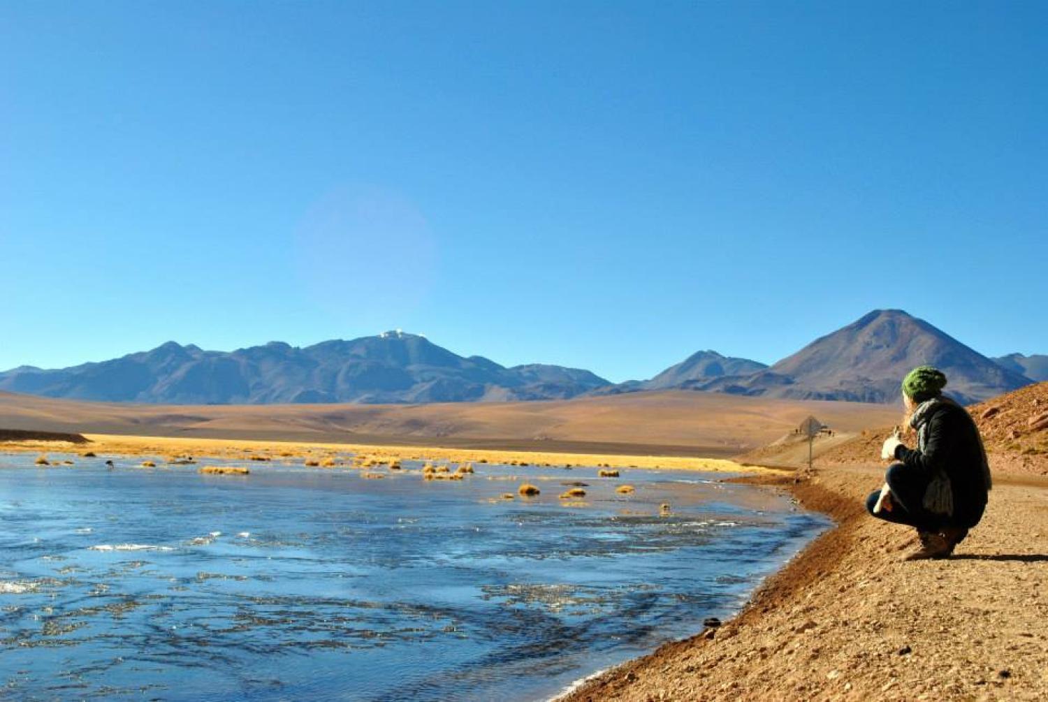 A student kneels by a lake in Chile