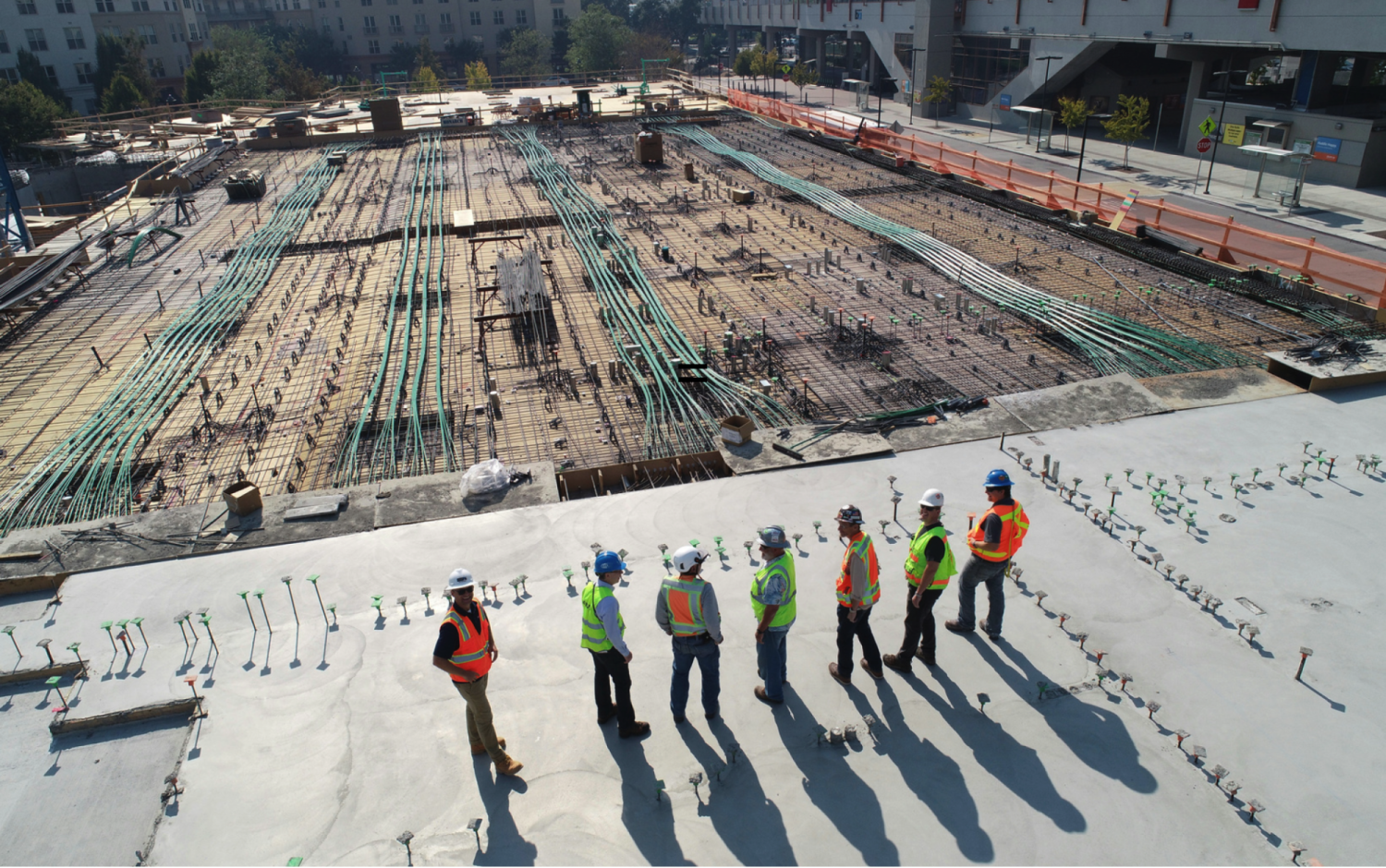 A group of people standing at a construction site in high vis vests and hard hats