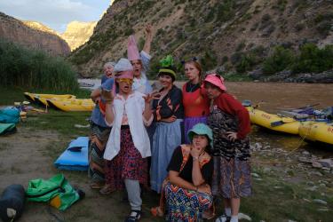 Students dressed in silly costumes pose on the bank of a river.