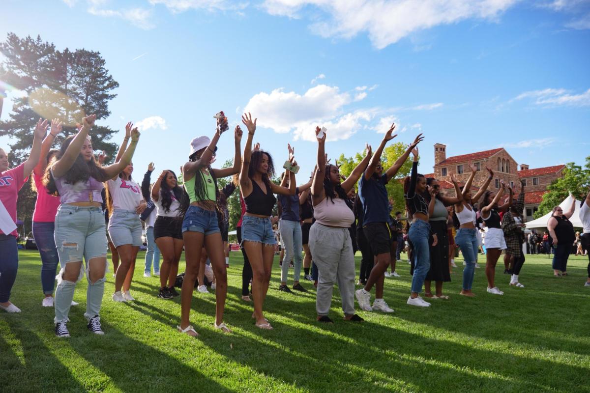 a large group of students dancing together on a field during CUnity Fest