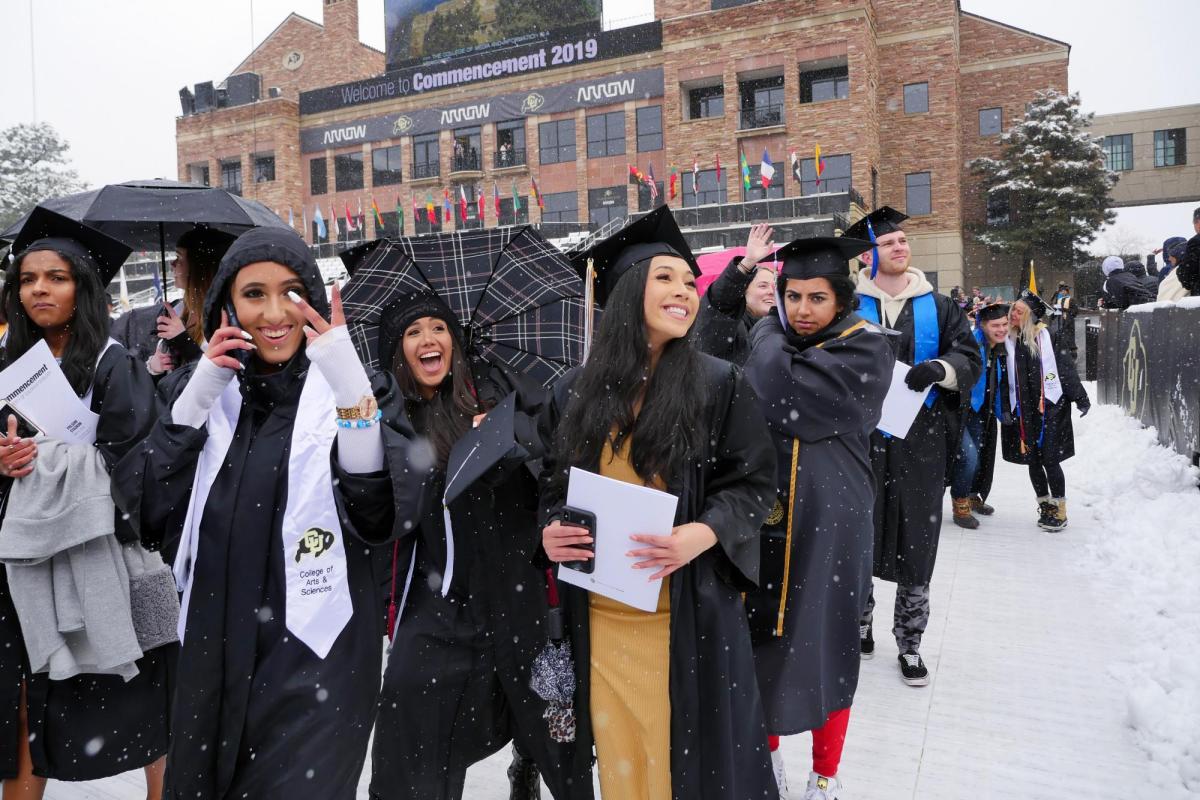 students during CU Boulder's May 2019 commencement, wearing grad regalia in the snow
