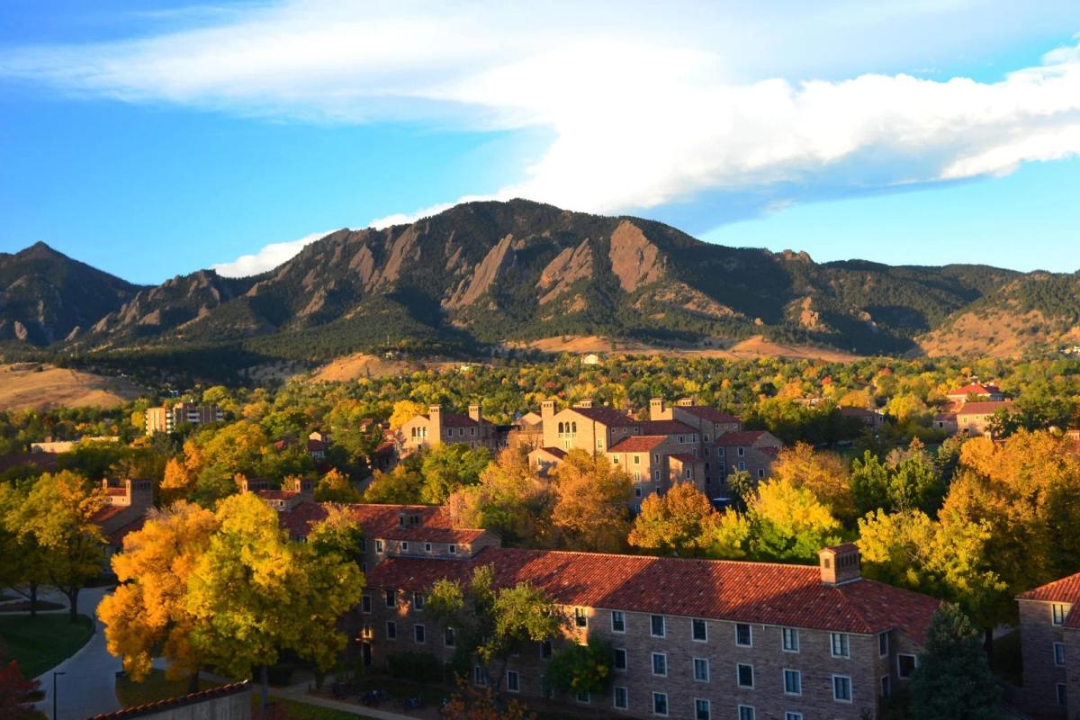 a view of campus with fall foliage and the flatirons in the background