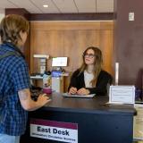 Student worker at the Norlin Library east desk helping a student