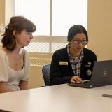 Library staff working with a student on a laptop