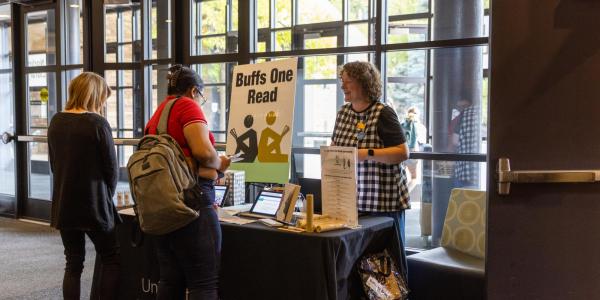 Librarian interacting with student at a Buffs One Read table