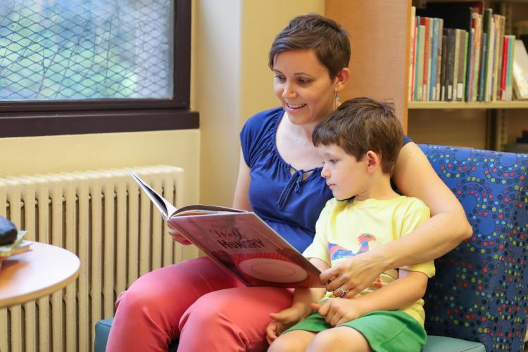 Faculty member Stephanie Bonjack reads to her young son in the CYAC section of Norlin.