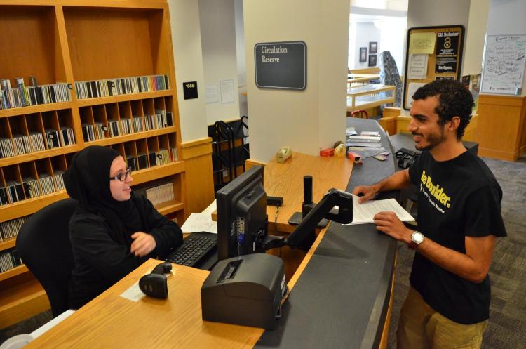 Circulation student assistant assists a patron at the desk of the Earth Sciences Library