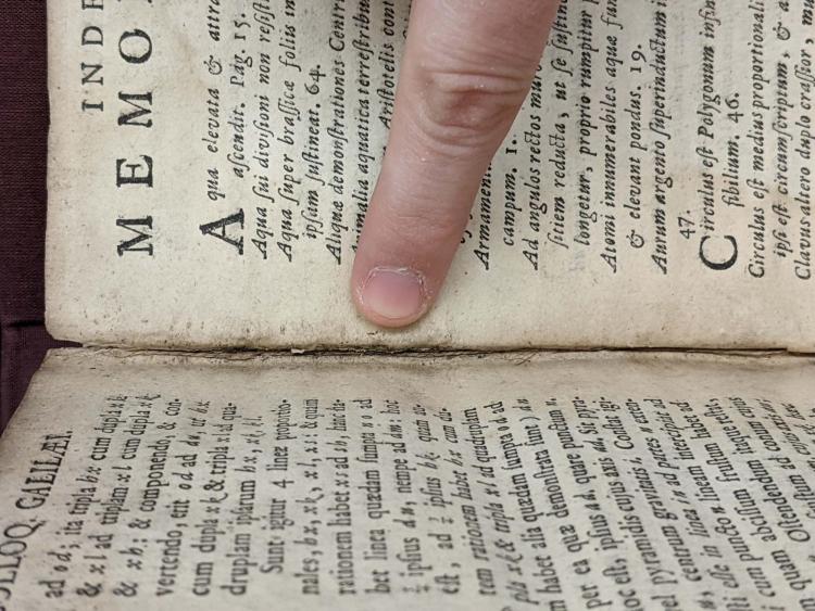  A finger points to wear and tear in the creases of the binding
