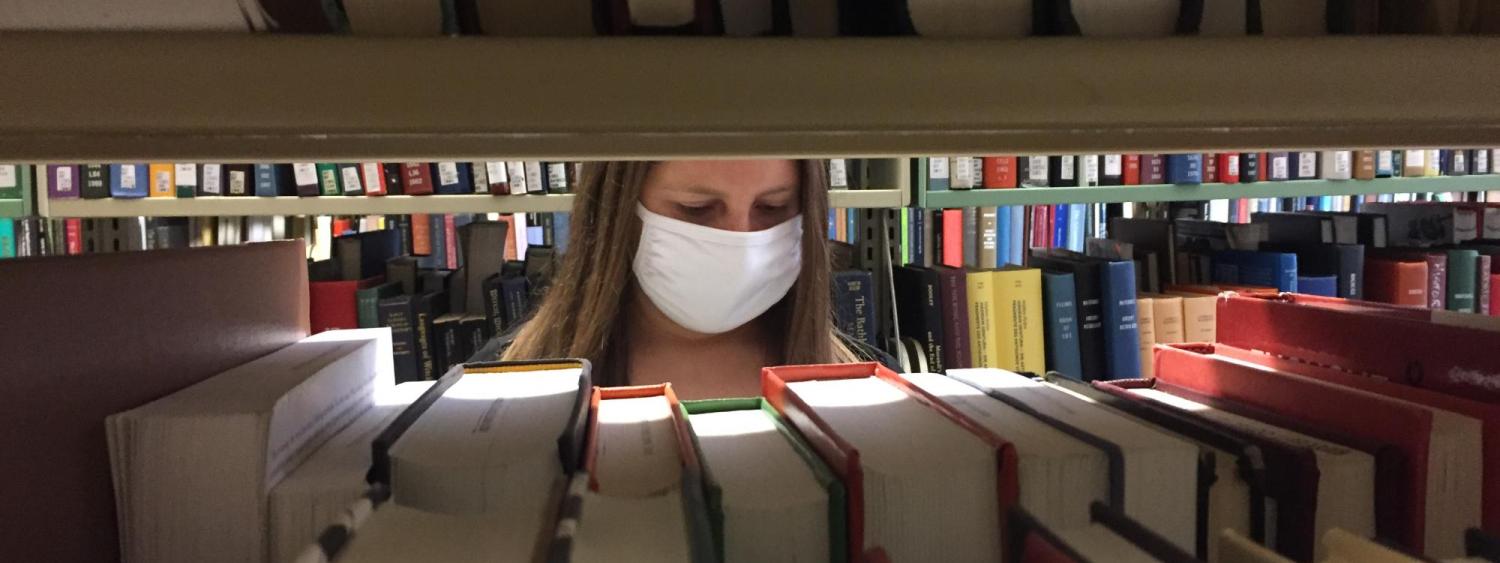 Circulation Media Specialist Arielle Fertman is looking for a patron request in the Norlin Library stacks.