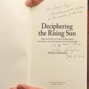 Archivist David Hays holding a copy of Deciphering the Rising Sun with a personal thank you inscription by the authors.