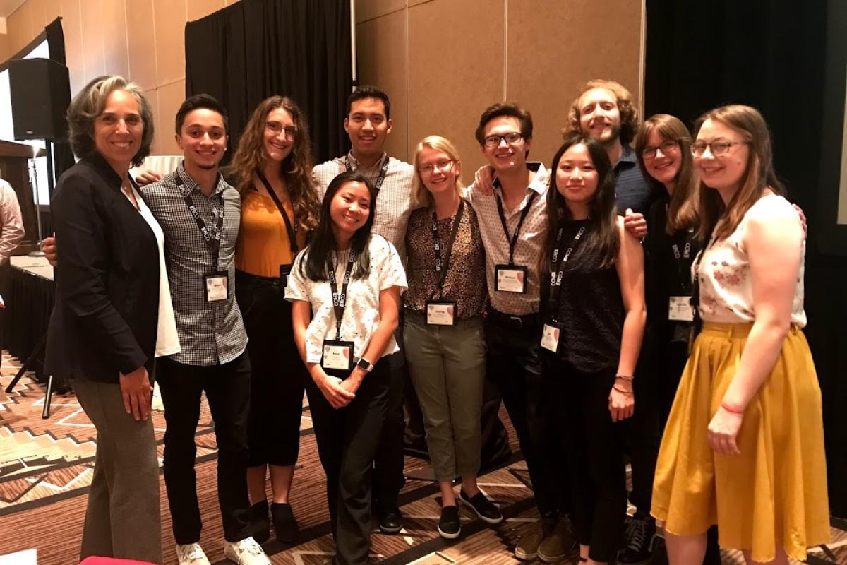 A group stands at a conference, smiling at the camera.