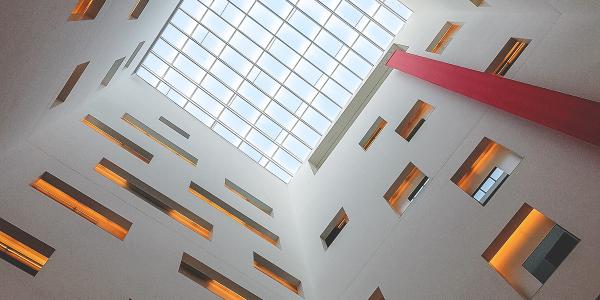 A photograph of a building interior showing a glass ceiling with orange-lit alcoves.