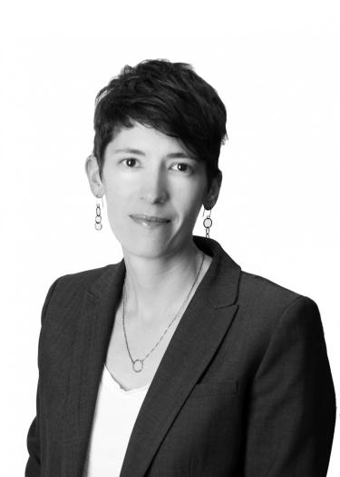 A black and white headshot of Rachel Fitzgerald with short dark hair and a suit.