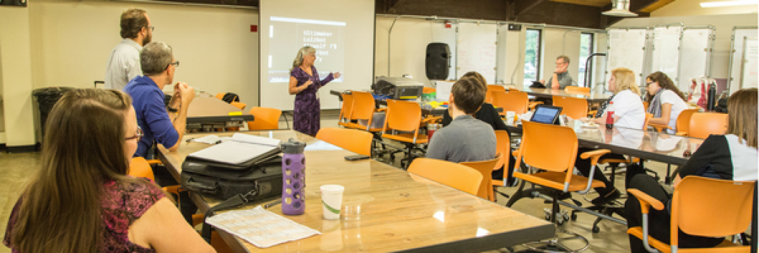 Professor leading a discussion with about a dozen conference attendees