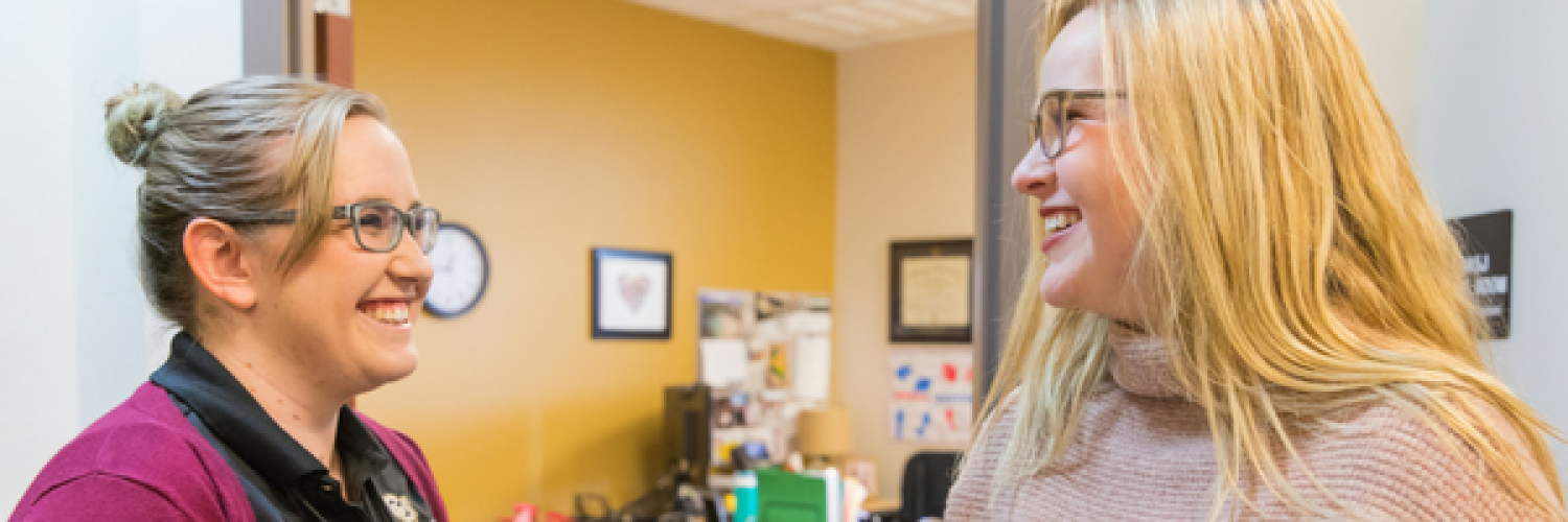 Two student staff members looking at each other and smiling