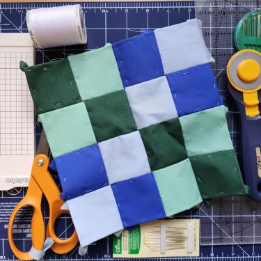 a photo of a 4x4 quilted collection of squares in blue and green