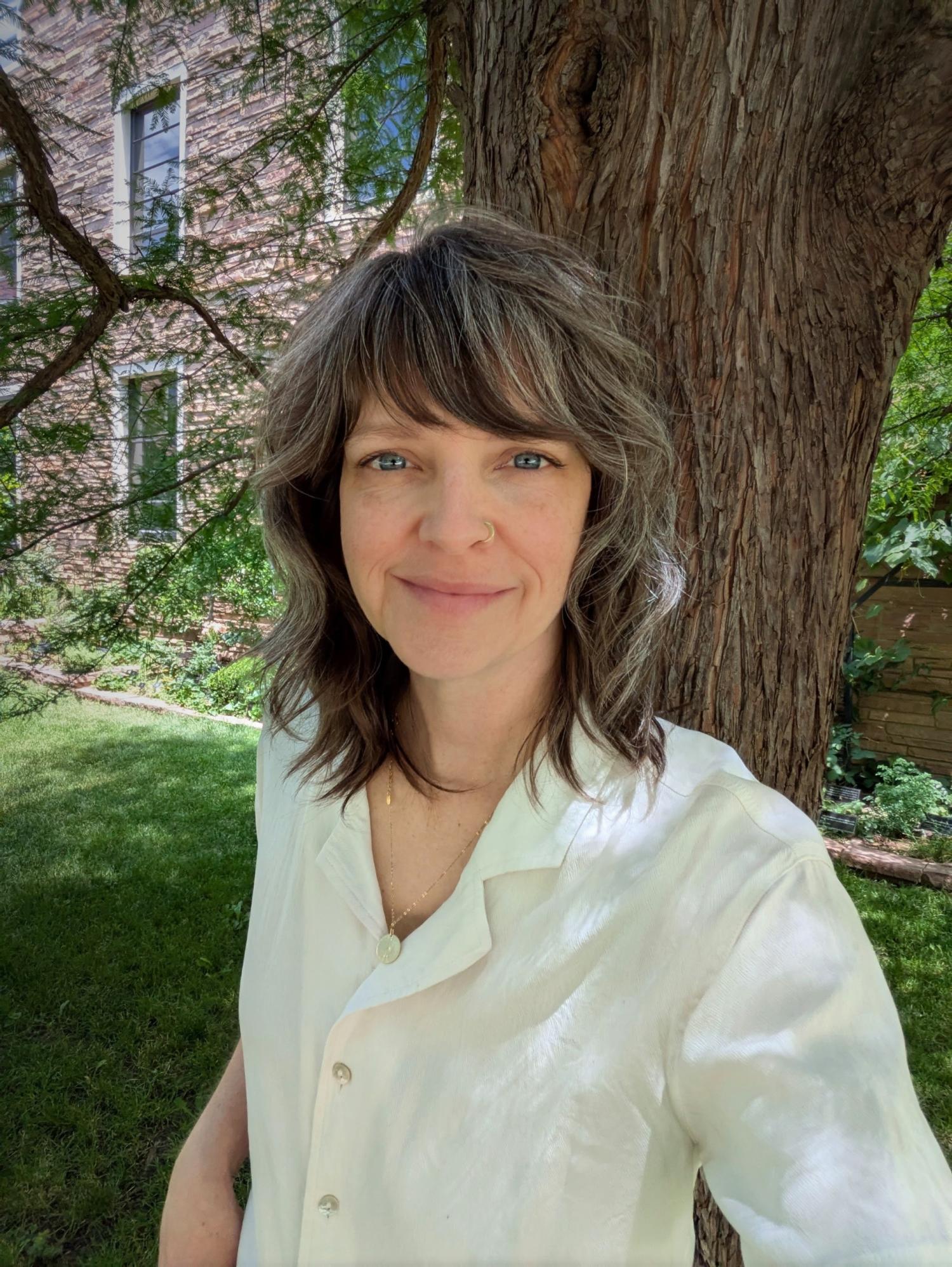 A photo of Jessica Holman standing in front of a tree, smiling
