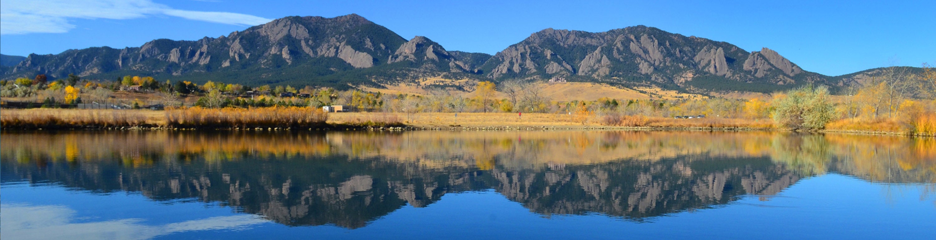 The Flatirons reflecting on a lake.