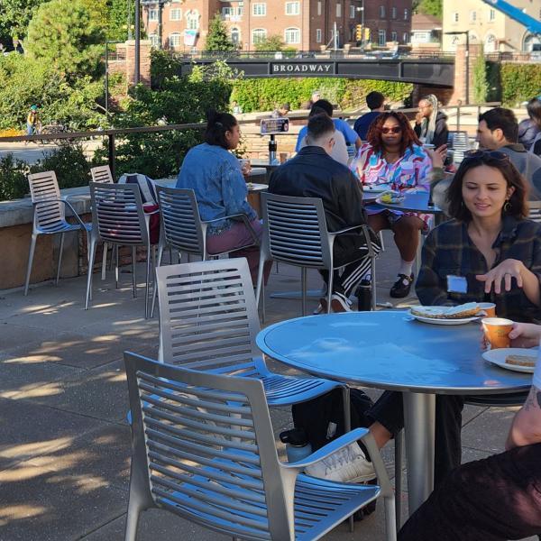 students on campus sitting and talking in a courtyard area with tables