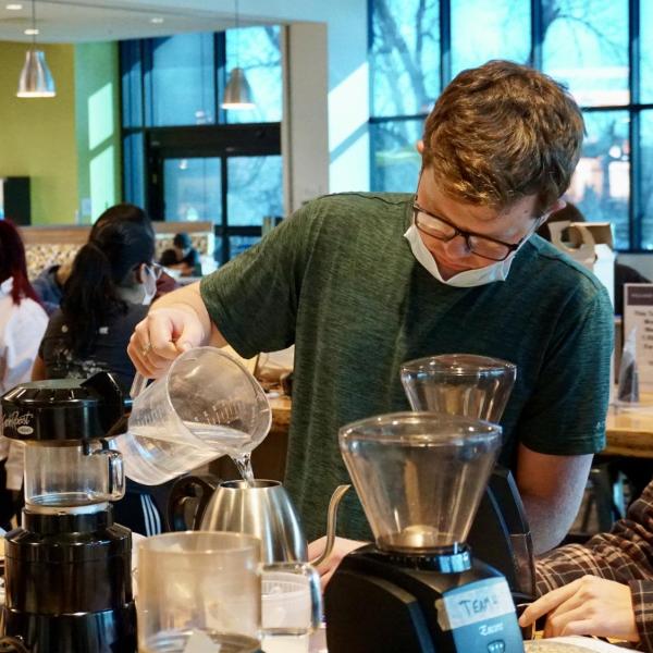 Student pours water into kettle for brewing