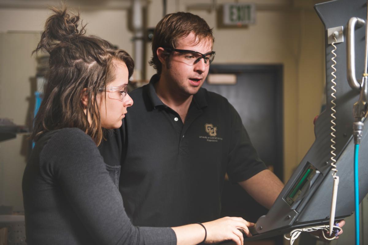 A students in the Ide Forge machine shop with an advisor. 