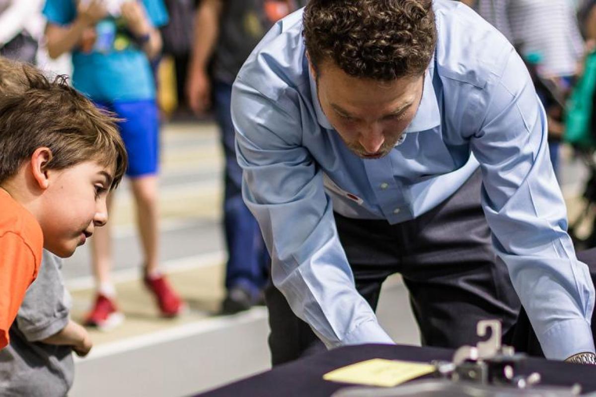 graduate student showing children his engineering project