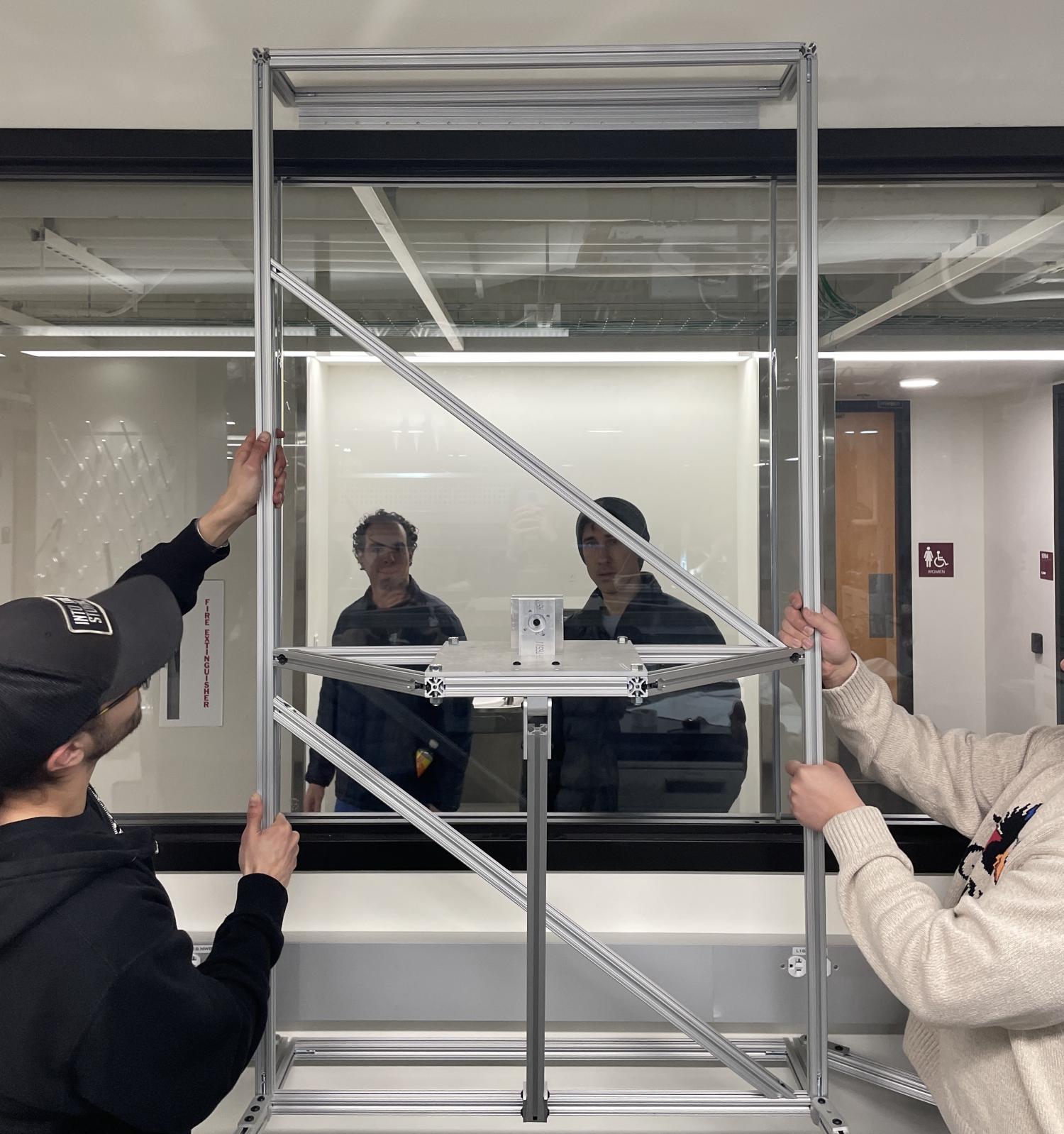 two men holding up a detachable aluminum frame in front of a window