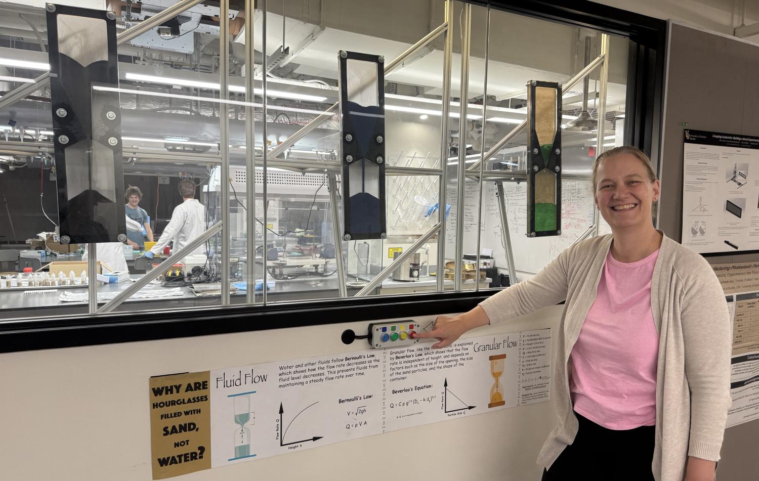 woman standing in front of motorized hourglass display in lab window