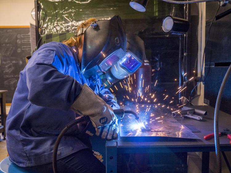 Two people welding in a machine shop