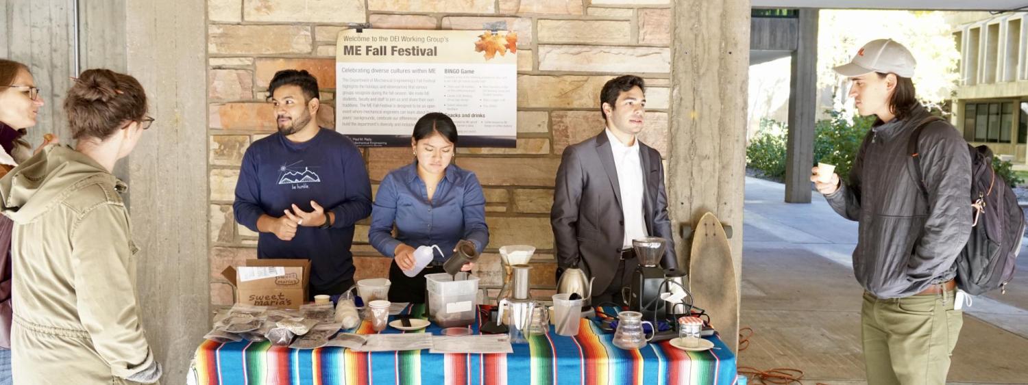 Students behind a colorful table brewing coffee