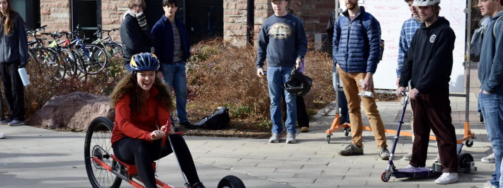 A student laughs as she races her drill-powered tricycle during the component design class runoff