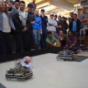 Two robots in the arena with students watching.