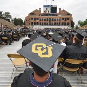 A student wearing a customized CU mortar board at a past campus graduation ceremony at Folsom Field