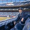 Man in blue Denver Broncos gear sitting in empty stands of Broncos stadium